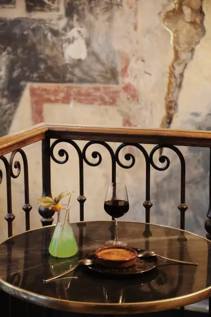 Rambarde en fer forgé, crème brûlée et verre de vin sur un guéridon