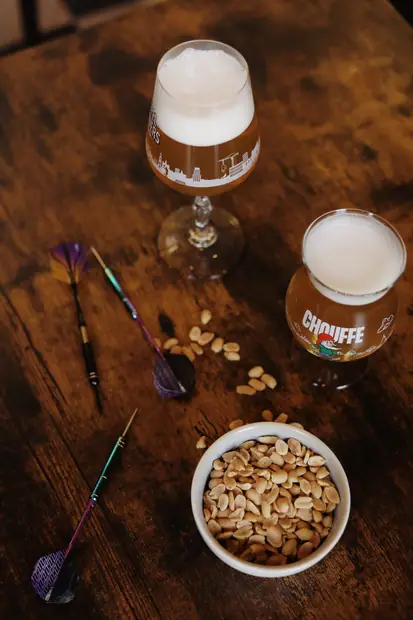 Chouffe, fléchettes et cacahuètes sur la table en bois